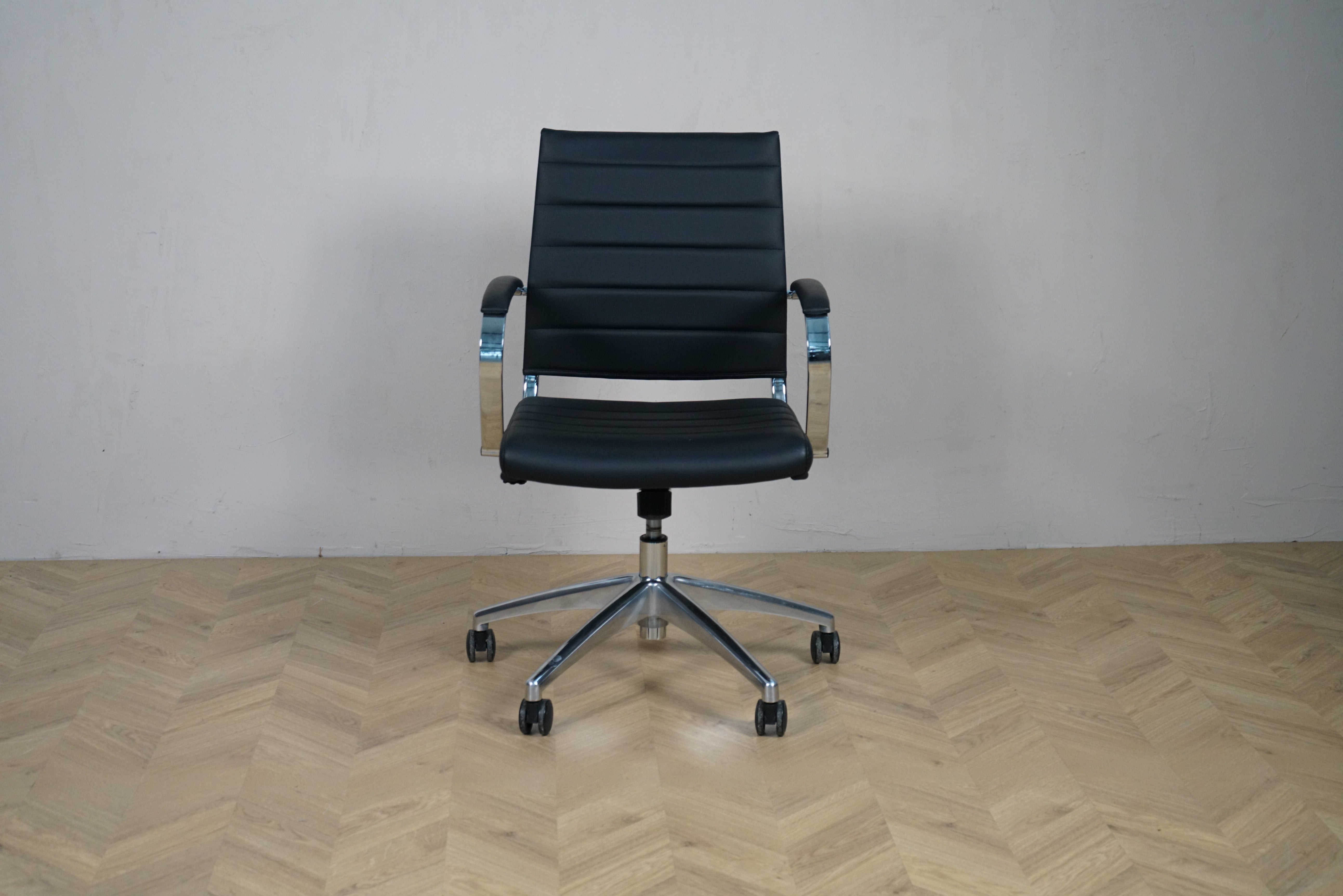 Konferencestol i sort kunstlæder med krom stel, armlæn og hjul – frontvisning